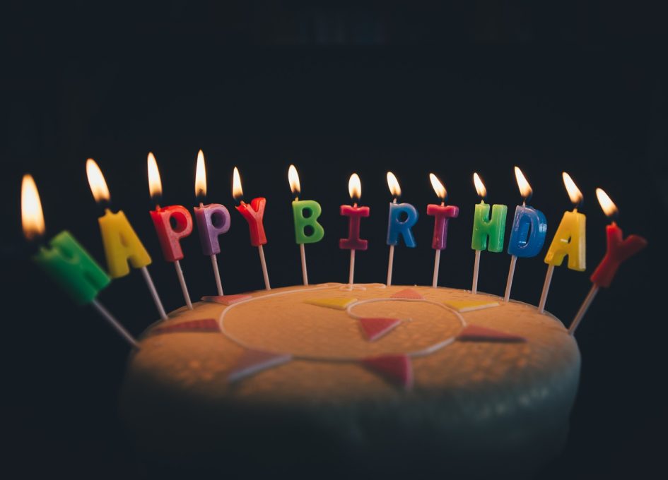 Image of a birthday cake with the words happy birthday spelt out in candles.